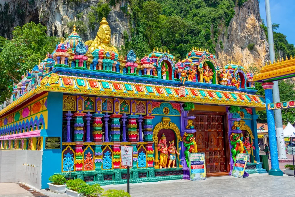 Brightly painted Hindu temple exterior near the entrance of Batu Caves, showcasing intricate statues and vivid colors.