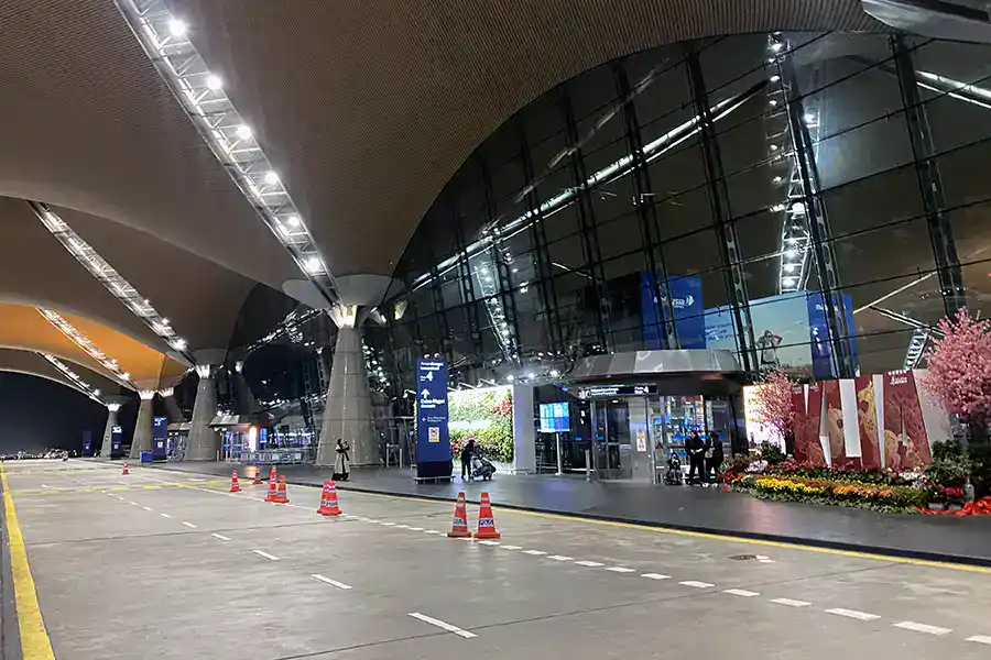 KLIA airport terminal exterior at night showing the modern curved roof architecture and departure drop-off area — the starting point for travellers getting to Batu Caves from the airport