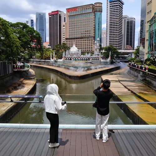 Kuala Lumpur River of Life – Tourist Spot on Batu Caves and City Tour Tourists photographing Jamek Mosque at Kuala Lumpur’s River of Life, a stop often included in Batu Caves and Kuala Lumpur city tours
