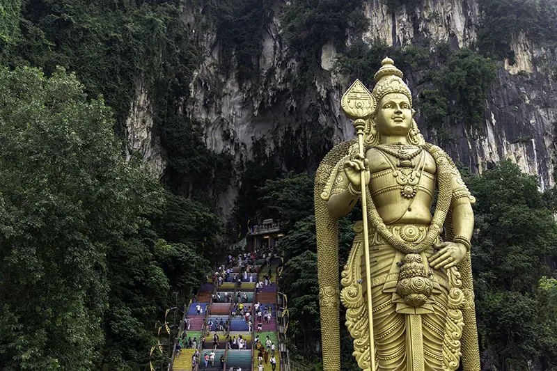 Batu Caves with giant Lord Murugan statue and colorful stairs, a top attraction for tourists on a layover in KL.