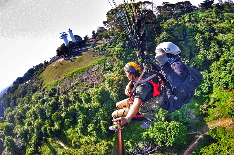 Tandem paragliding flight above lush green hills at Bukit Jugra, Selangor