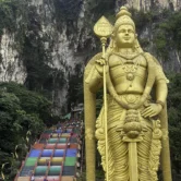 Golden Lord Murugan statue and rainbow steps at Batu Caves, a free stop included with the Malaysia Elephant Sanctuary tour from Kuala Lumpur.