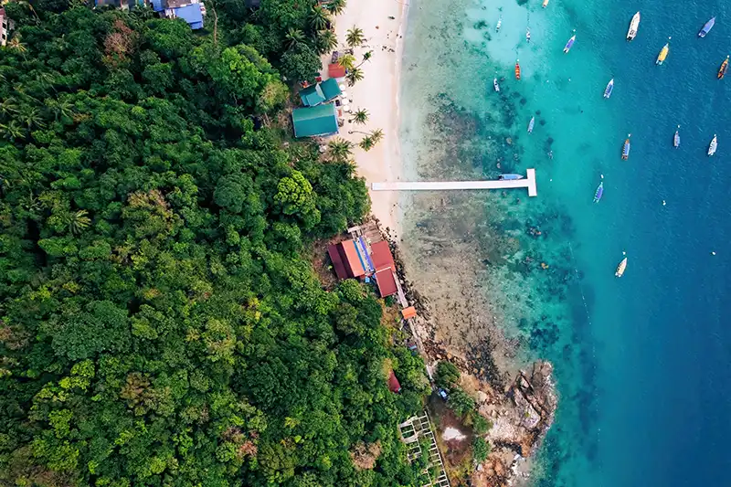 Aerial view of Perhentian Kecil Island Malaysia with white sandy beach, tropical forest, and turquoise waters dotted with boats