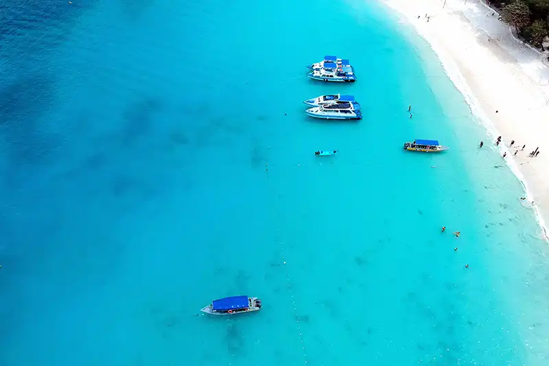 Aerial view of Redang Island Malaysia with turquoise water, white sandy beach, and boats anchored near the shore