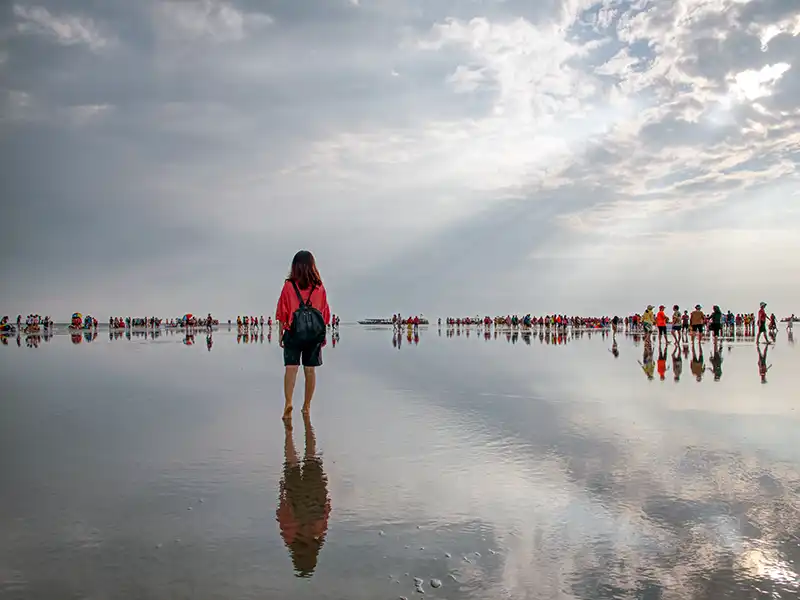 Visitors walking on the reflective sandbank at Sky Mirror in Kuala Selangor