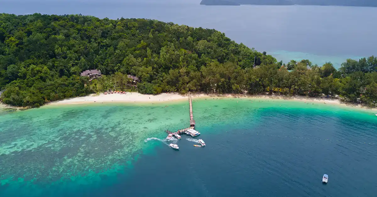 Aerial view of a tropical island in Malaysia with clear water and forested coastline