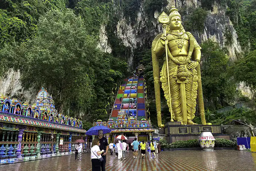Batu Caves entrance and Lord Murugan statue after rain with wet courtyard in Kuala Lumpur