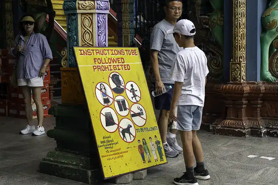 Visitor reading the Batu Caves dress code instructions sign near the temple entrance in Selangor