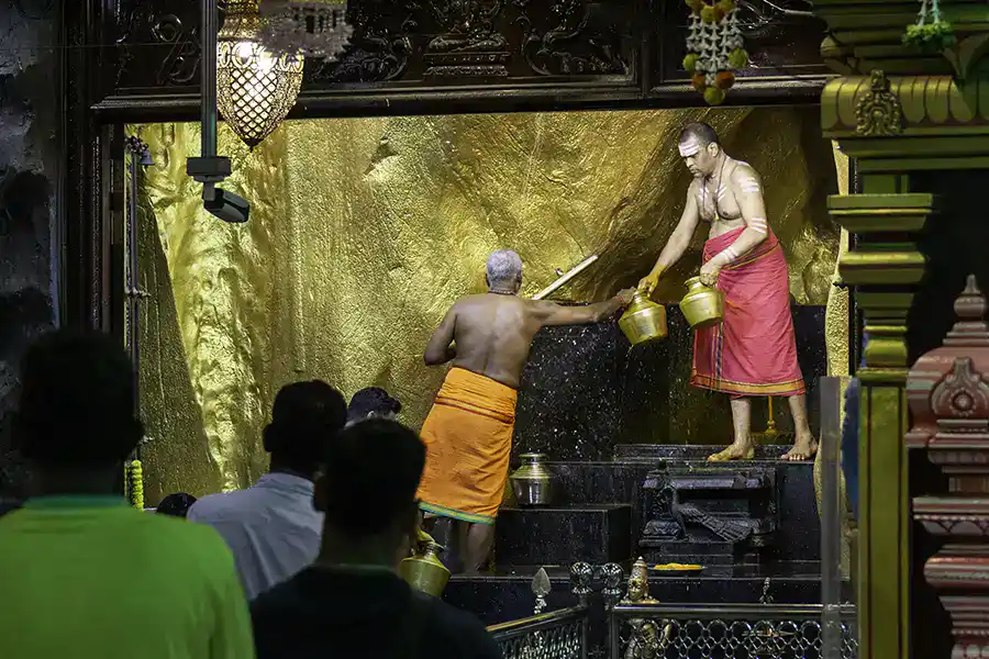 Hindu priest performing puja ritual inside Batu Caves temple in Kuala Lumpur