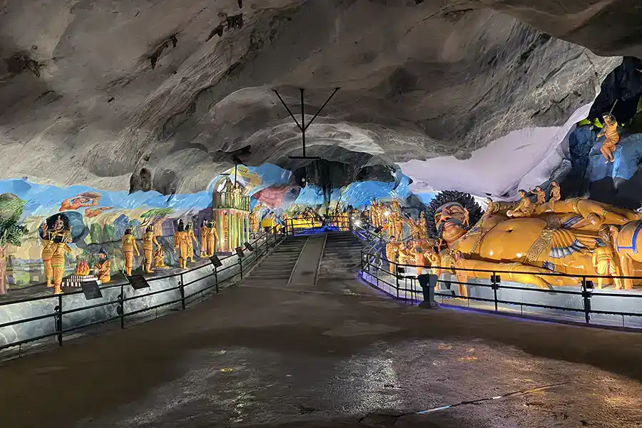 Inside Ramayana Cave at Batu Caves showing colourful statues and painted murals depicting Hindu mythology, including the giant sleeping Kumbhakarna figure