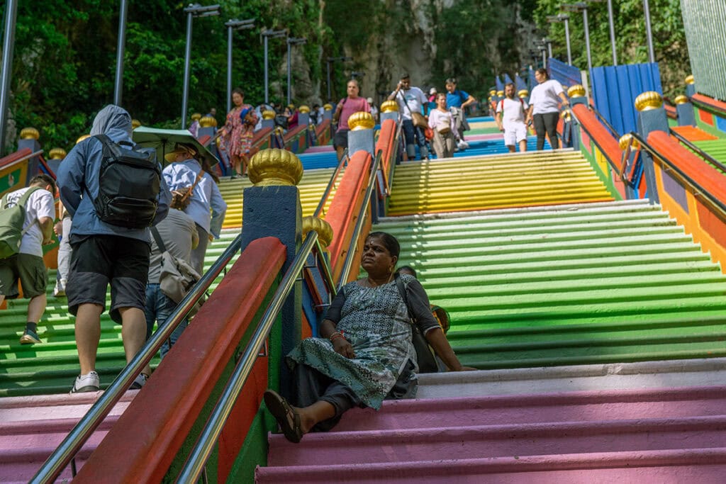 Visitor resting in the shade on the Batu Caves staircase during the climb to the Temple Cave