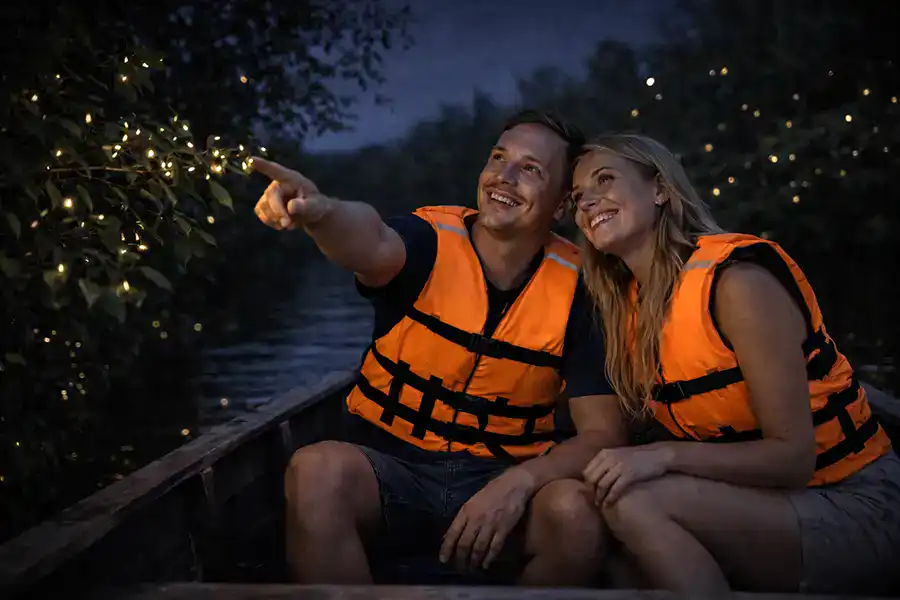A couple on a boat watching fireflies light up the mangrove trees along the Selangor River at night during a Kuala Selangor fireflies tour