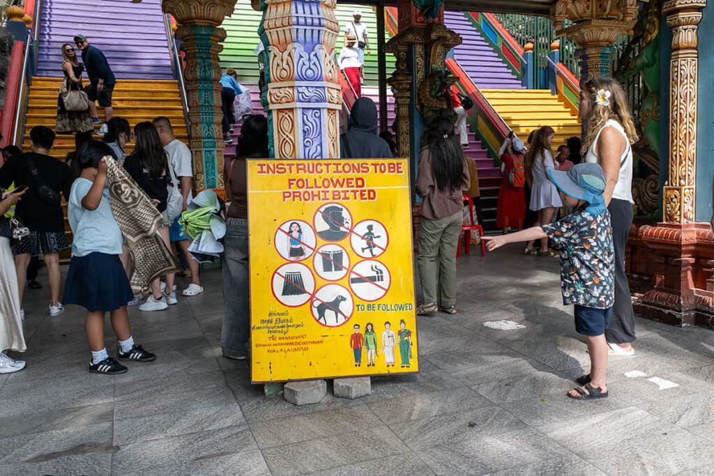 Official Batu Caves dress code signboard marking where clothing rules are enforced before climbing the 272-step staircase