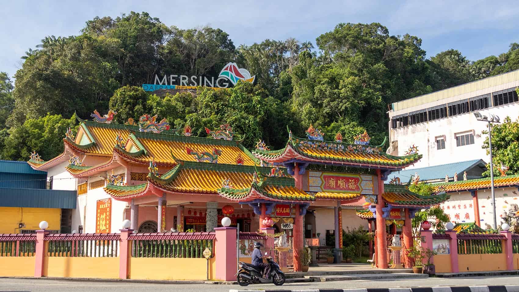 Mersing town centre with a Chinese temple in the foreground and the Mersing district sign on the hill behind