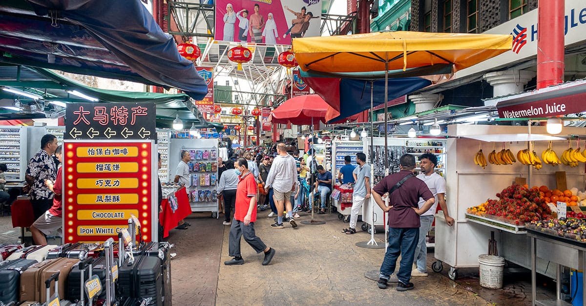 Petaling Street market in Chinatown Kuala Lumpur — covered walkway with red lanterns, souvenir stalls, and fruit vendors