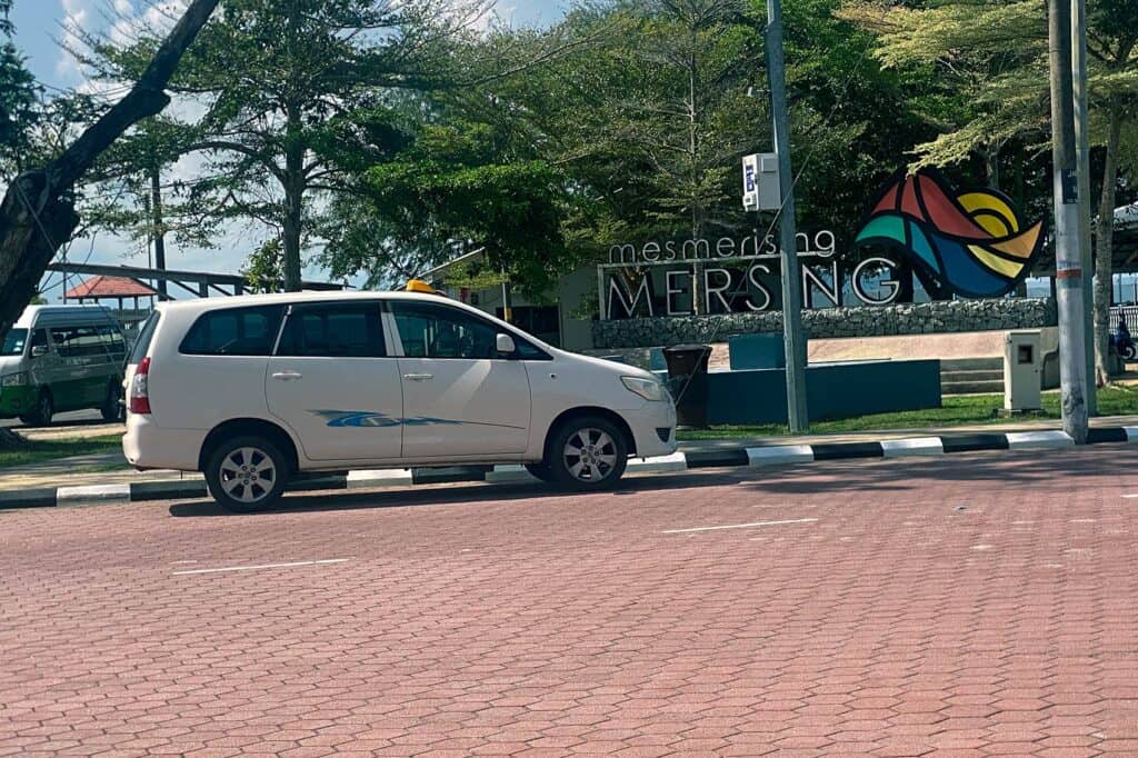 Private transfer vehicle waiting at Mersing Jetty with the Mesmerising Mersing welcome sign in the background — door-to-door transfer from Kuala Lumpur to Mersing