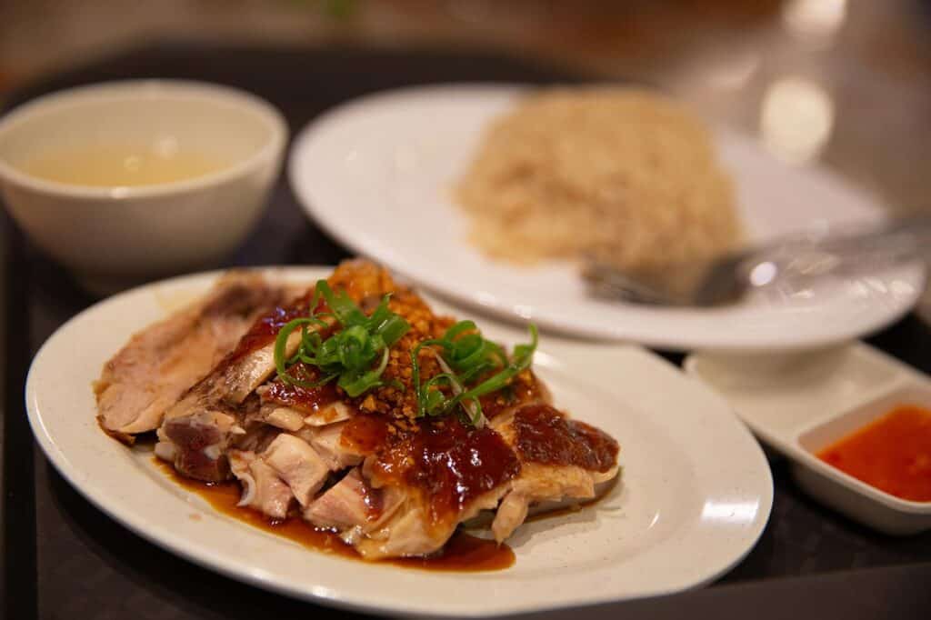 Sliced roasted chicken with soy glaze served with fragrant rice, clear soup and chilli sauce — a classic Chinese-Malaysian dish and one of the best things to do in Kuala Lumpur for food lovers