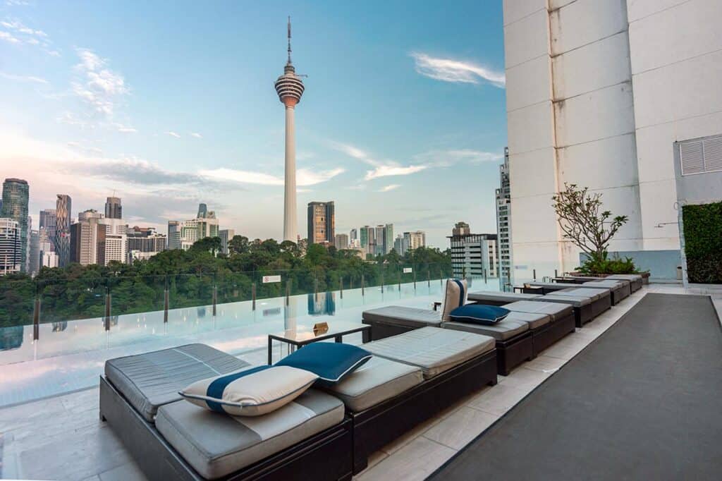 Rooftop infinity pool and lounge with KL Tower and Kuala Lumpur skyline in the background at dusk — one of the most relaxing evening experiences above the city