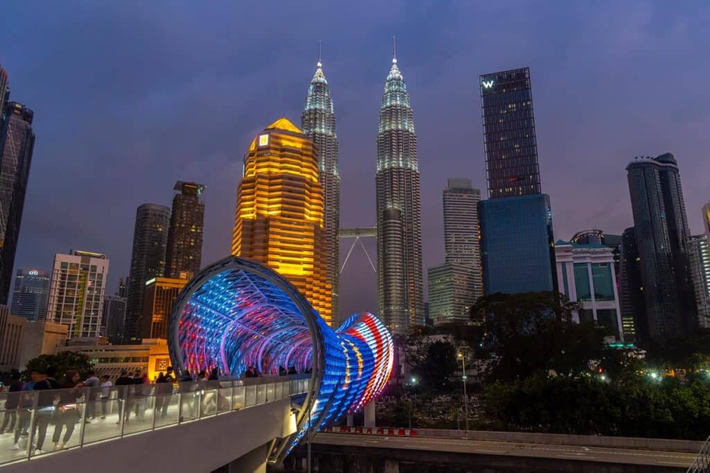 Saloma Bridge illuminated with LED lights at night with the Petronas Twin Towers and Kuala Lumpur skyline in the background