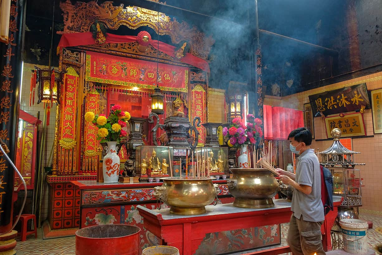 Worshipper burning incense at the altar inside Sin Sze Si Ya Temple — the oldest Taoist temple in Kuala Lumpur, built in the 1860s in Chinatown