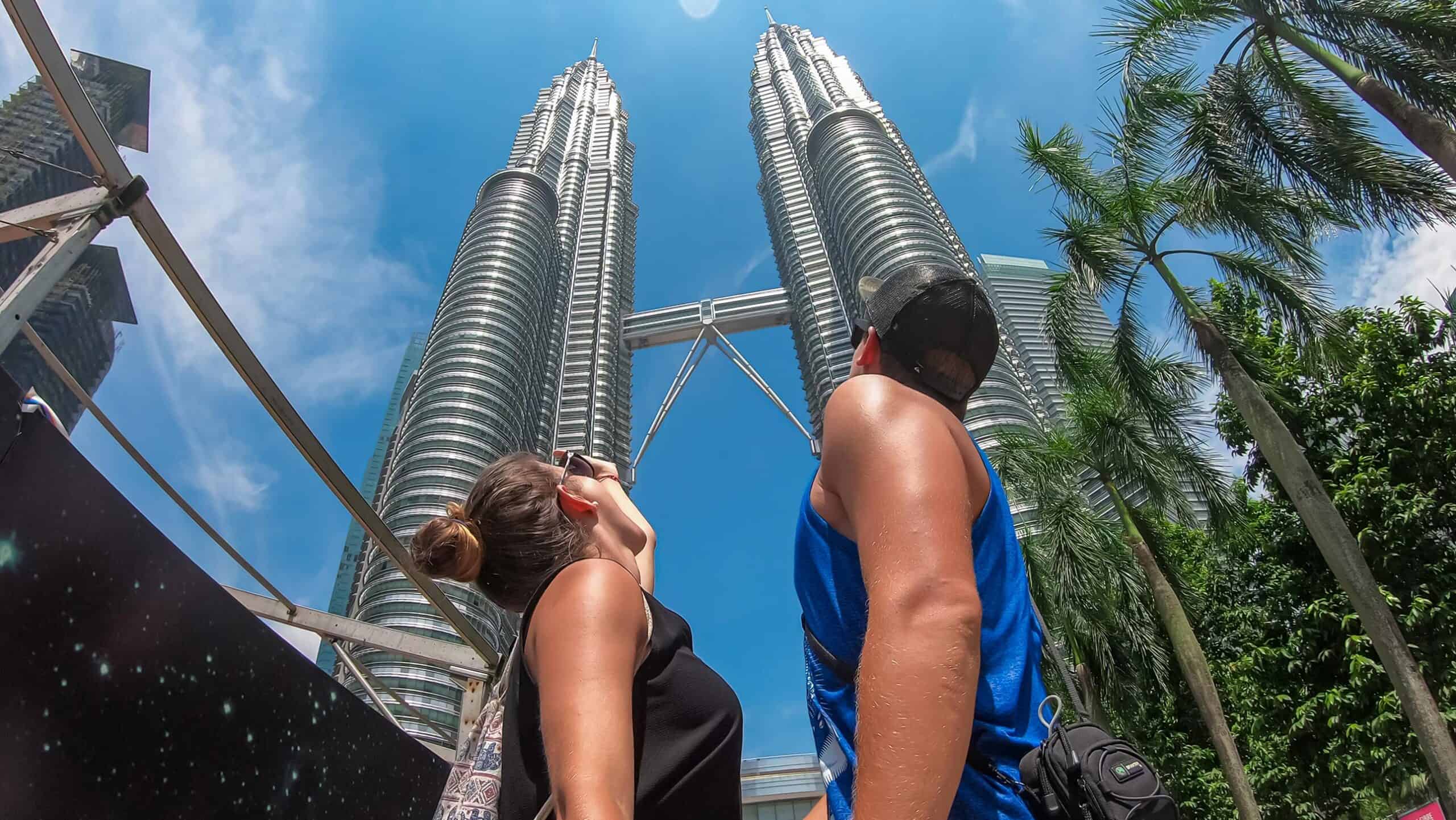 Tourists looking up at the Petronas Twin Towers from KLCC Park — the most iconic things to do in Kuala Lumpur for first-time visitors