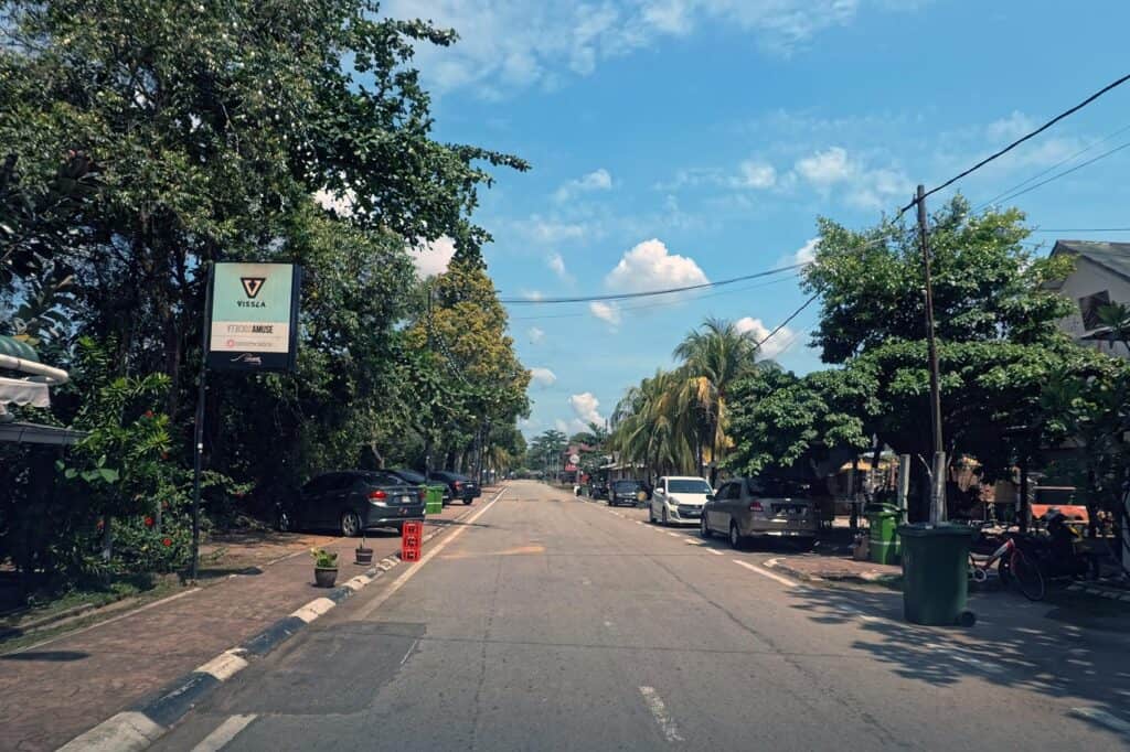 Main street through Cherating village, Pahang — narrow tree-lined road with street parking on both sides