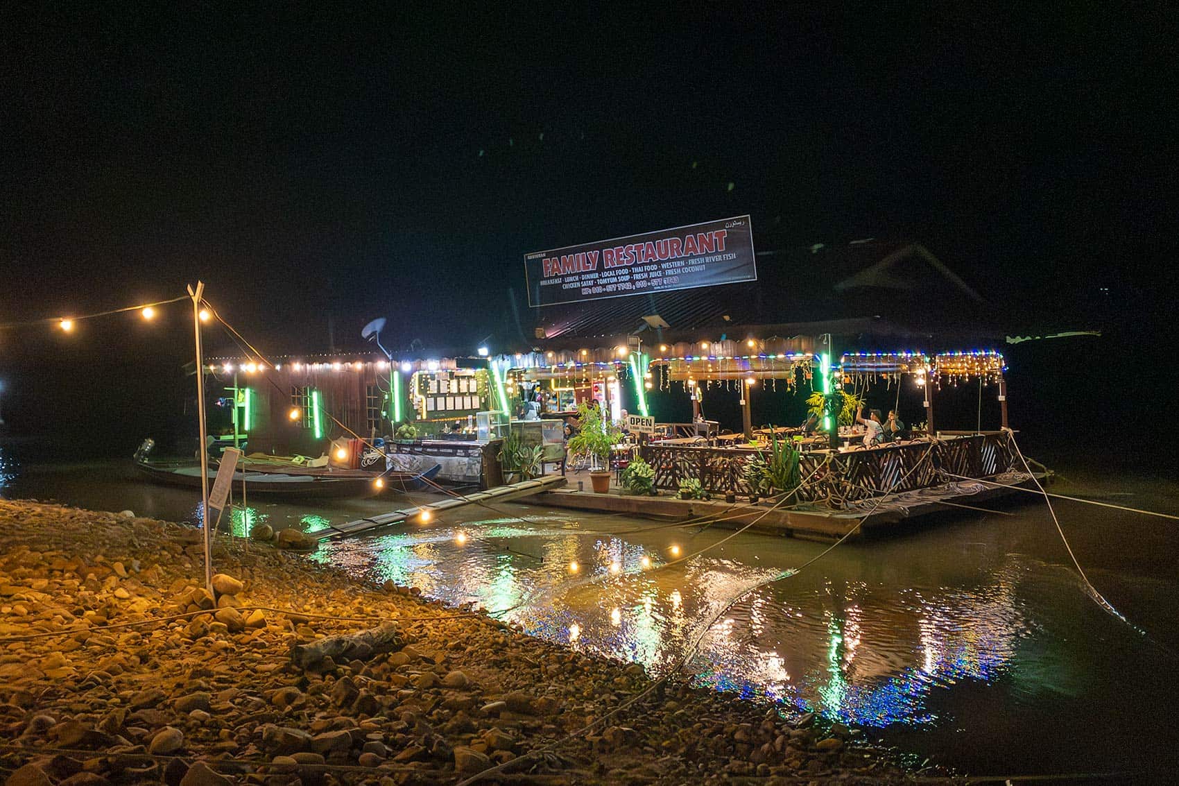 Floating Family Restaurant lit up at night on the Tembeling River in Kuala Tahan — dining in Taman Negara Pahang