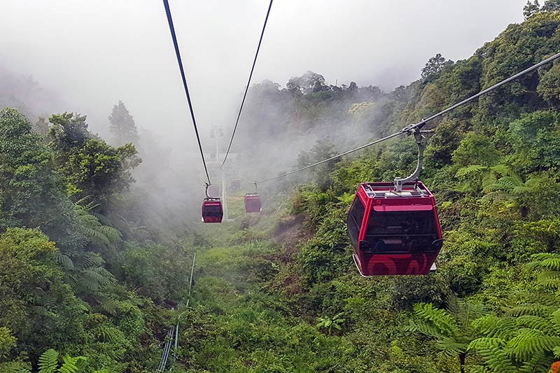 Red cable car gondolas ascending through misty forest at Genting Highlands, Pahang