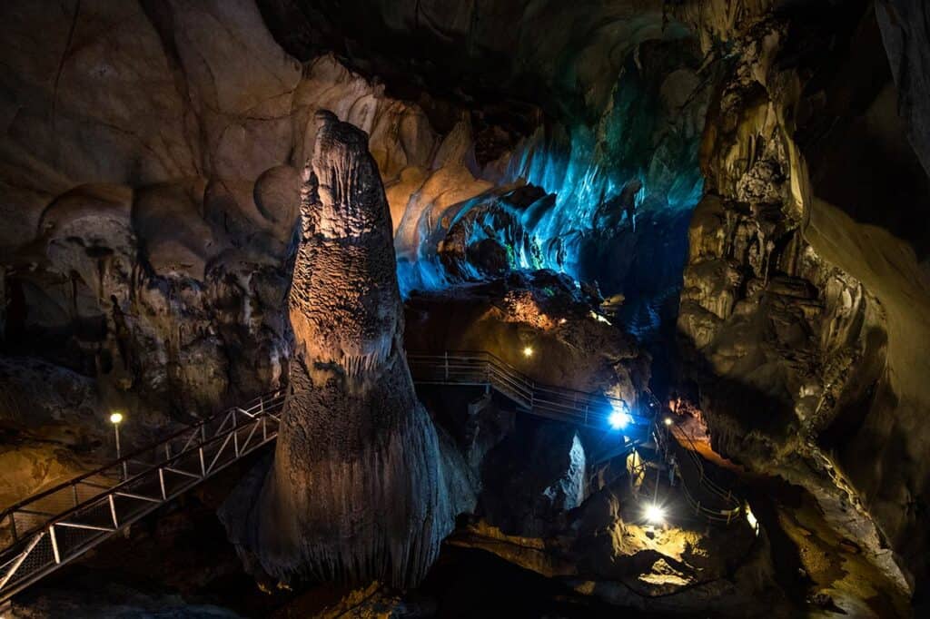 Giant stalagmite column inside Gua Tempurung limestone cave with lit walkway in Ipoh Malaysia