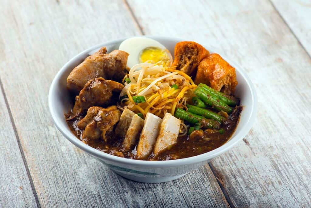 Ipoh curry mee bowl with dark rich broth tofu puffs boiled egg and bean sprouts Malaysia
