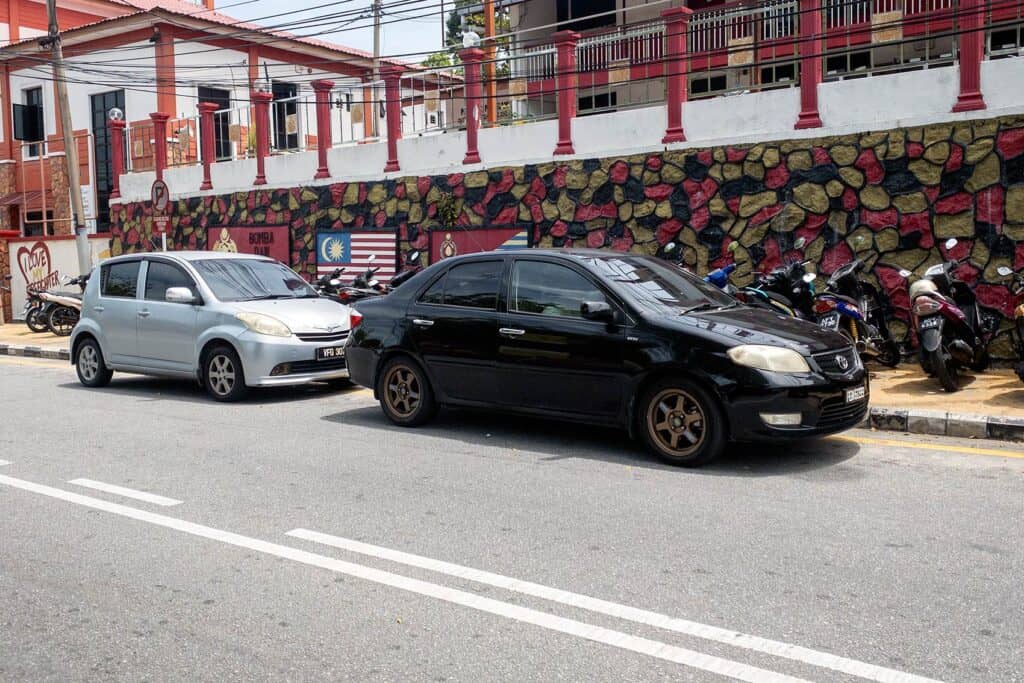 Cars parked on a street in Pangkor Island town — self-drive car rental is available at RM70 to RM80 per day for visitors who prefer four wheels