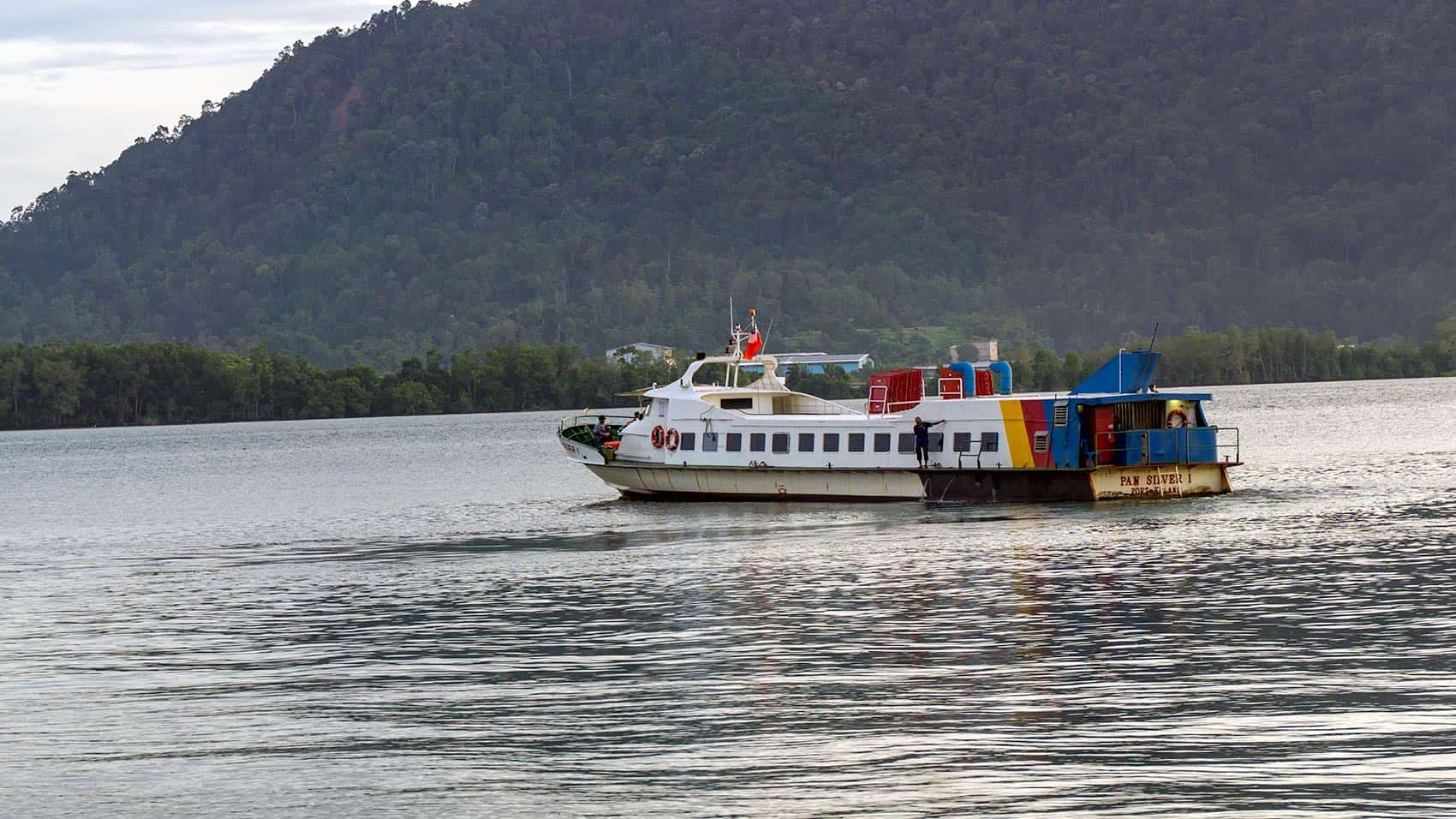 The PAN SILVER 1 Pangkor Island ferry departing Lumut Jetty at dawn with Pangkor Island's forested hills in the background