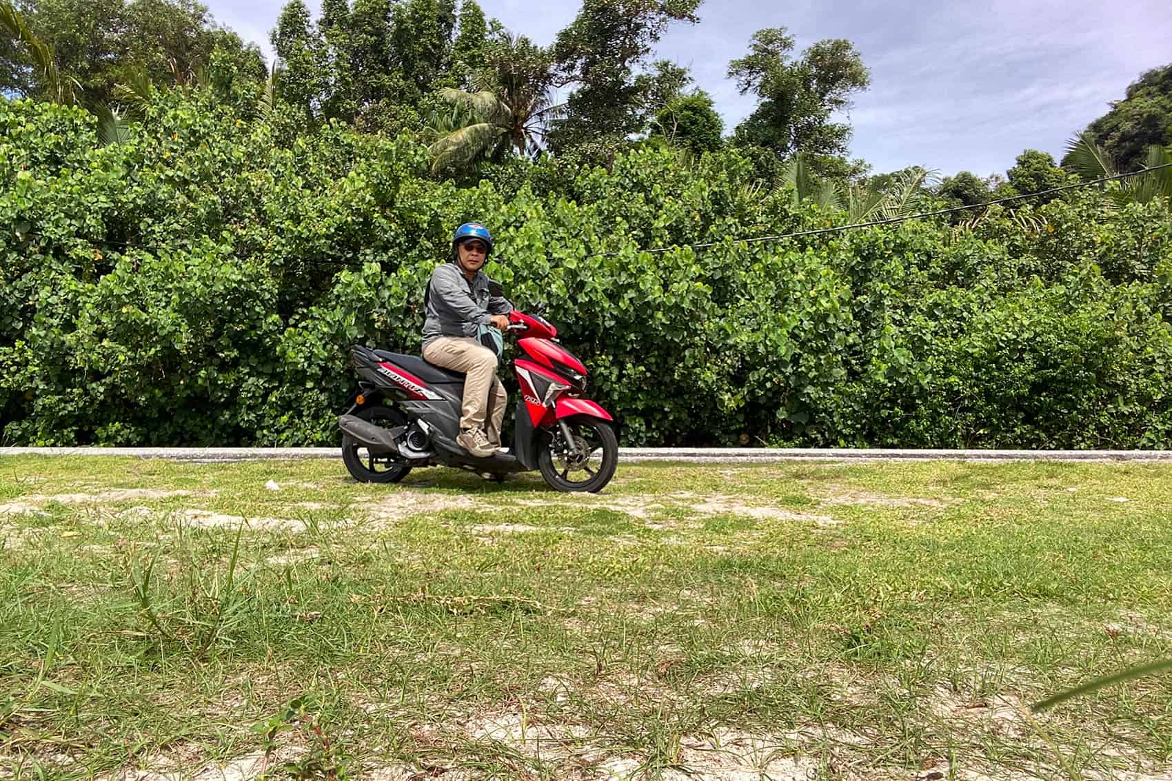 Anuar riding a rented red automatic scooter on Pangkor Island — motorcycle rental from RM40 per day is the most practical way to explore the island independently