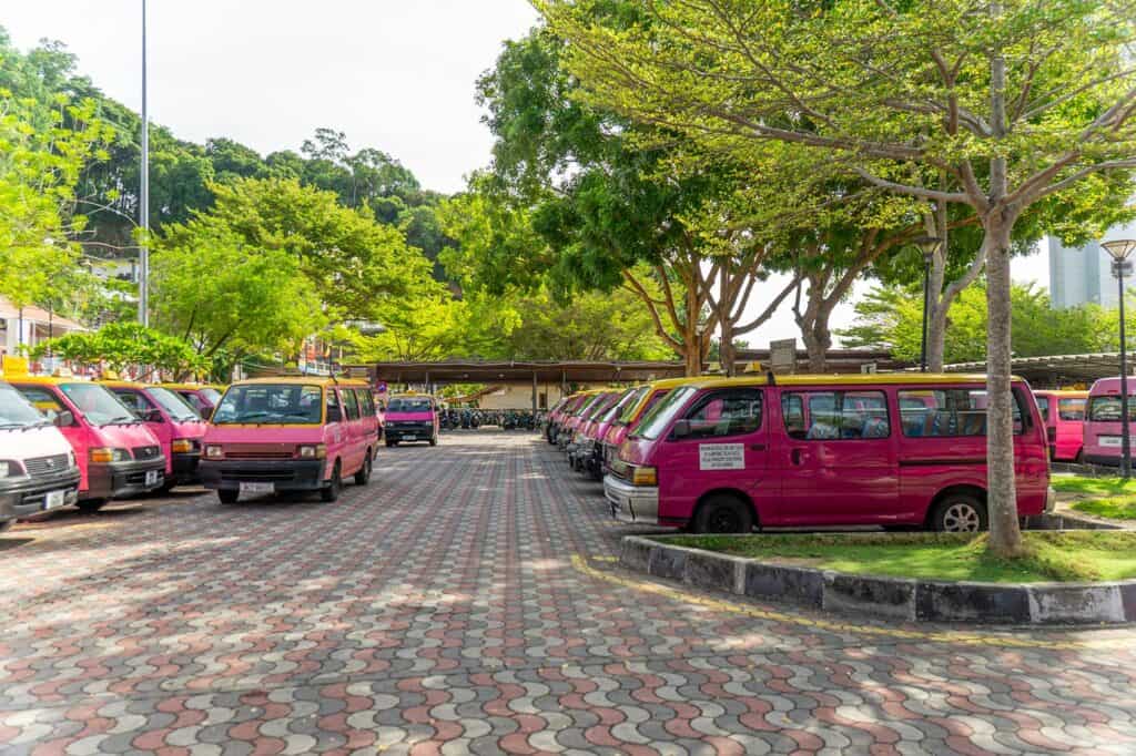Rows of pink Toyota taxi vans with yellow rooftop signs lined up at the Pangkor Island taxi rank near Pangkor Jetty — fixed-fare transport serving all major destinations on the island