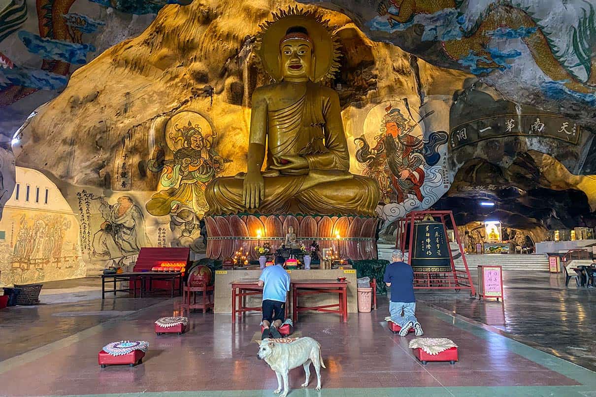 Golden Buddha statue and cave murals inside Perak Tong Cave Temple in Ipoh Malaysia