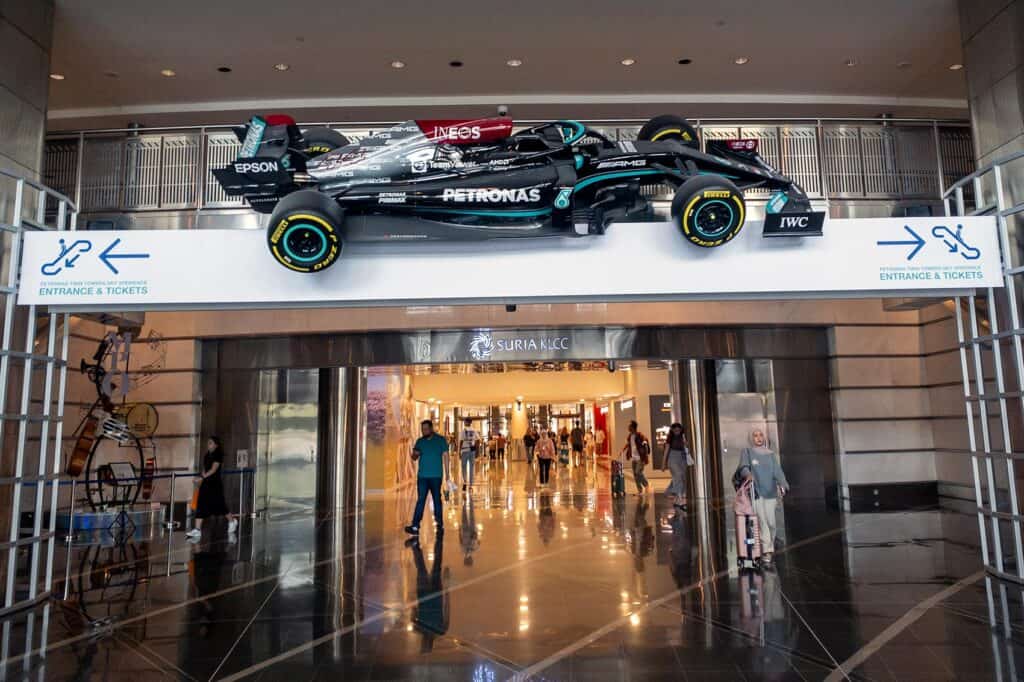 Petronas F1 car mounted above the central court with Sky Xperience Entrance and Tickets directional arrows pointing left and right
