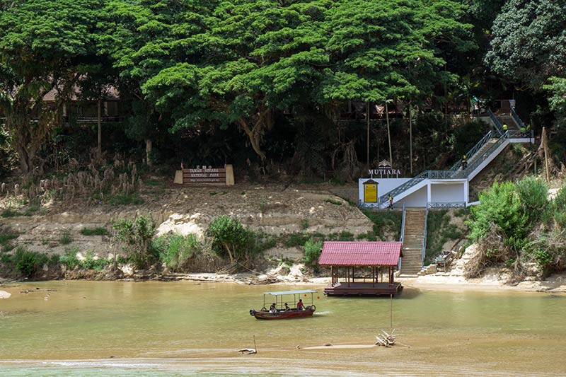 River boat crossing the Sungai Tembeling at Kuala Tahan with the Taman Negara National Park entrance and Mutiara resort visible on the riverbank, Pahang