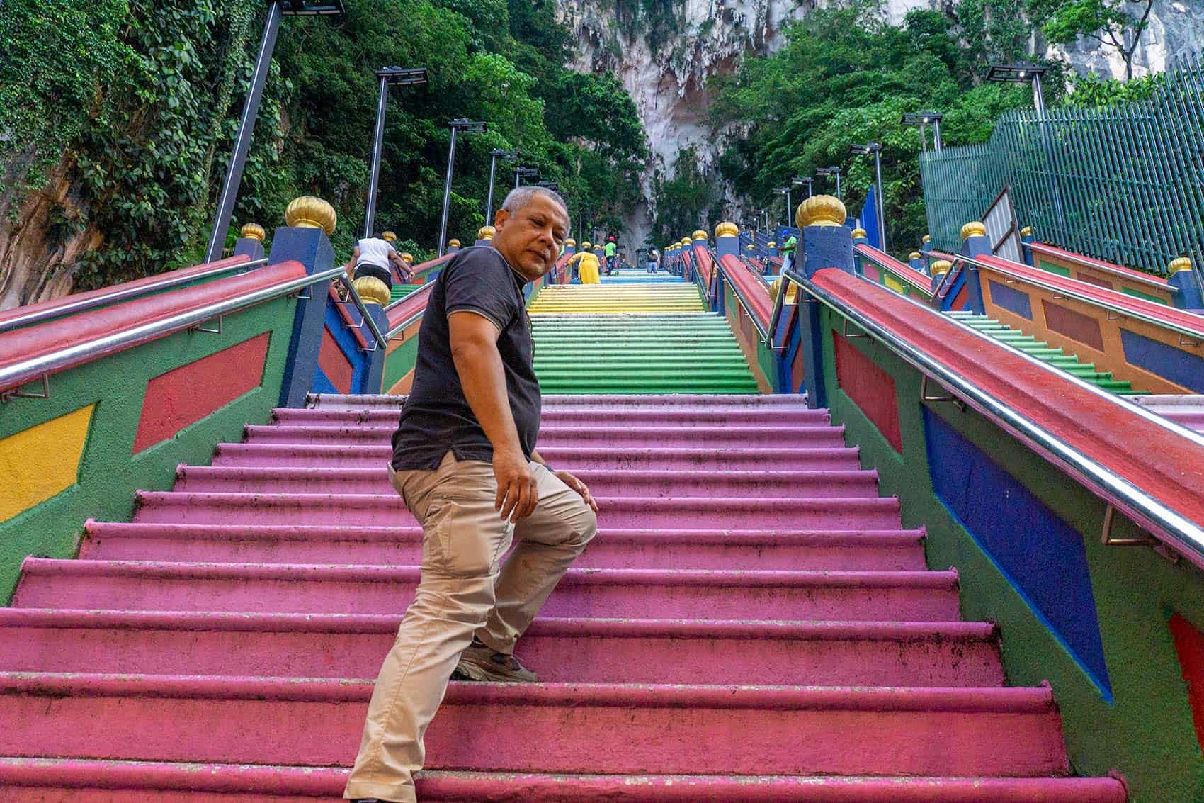 Anuar, founder of We Go With Anuar, climbing the rainbow-painted Batu Caves steps during a content verification visit — batu caves steps guide