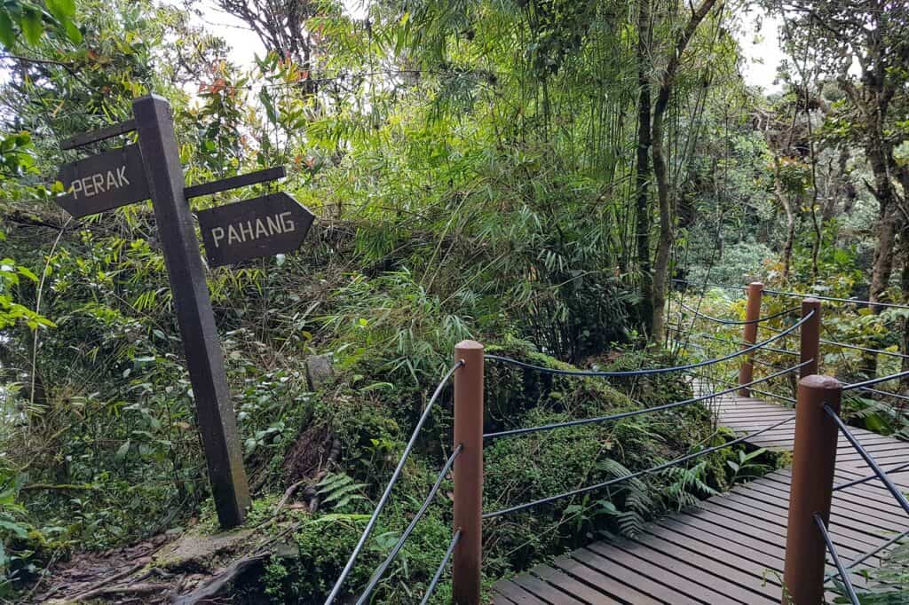irectional sign marking the Perak-Pahang state border on the boardwalk at Taman Eko Rimba Mossy Forest, Cameron Highlands