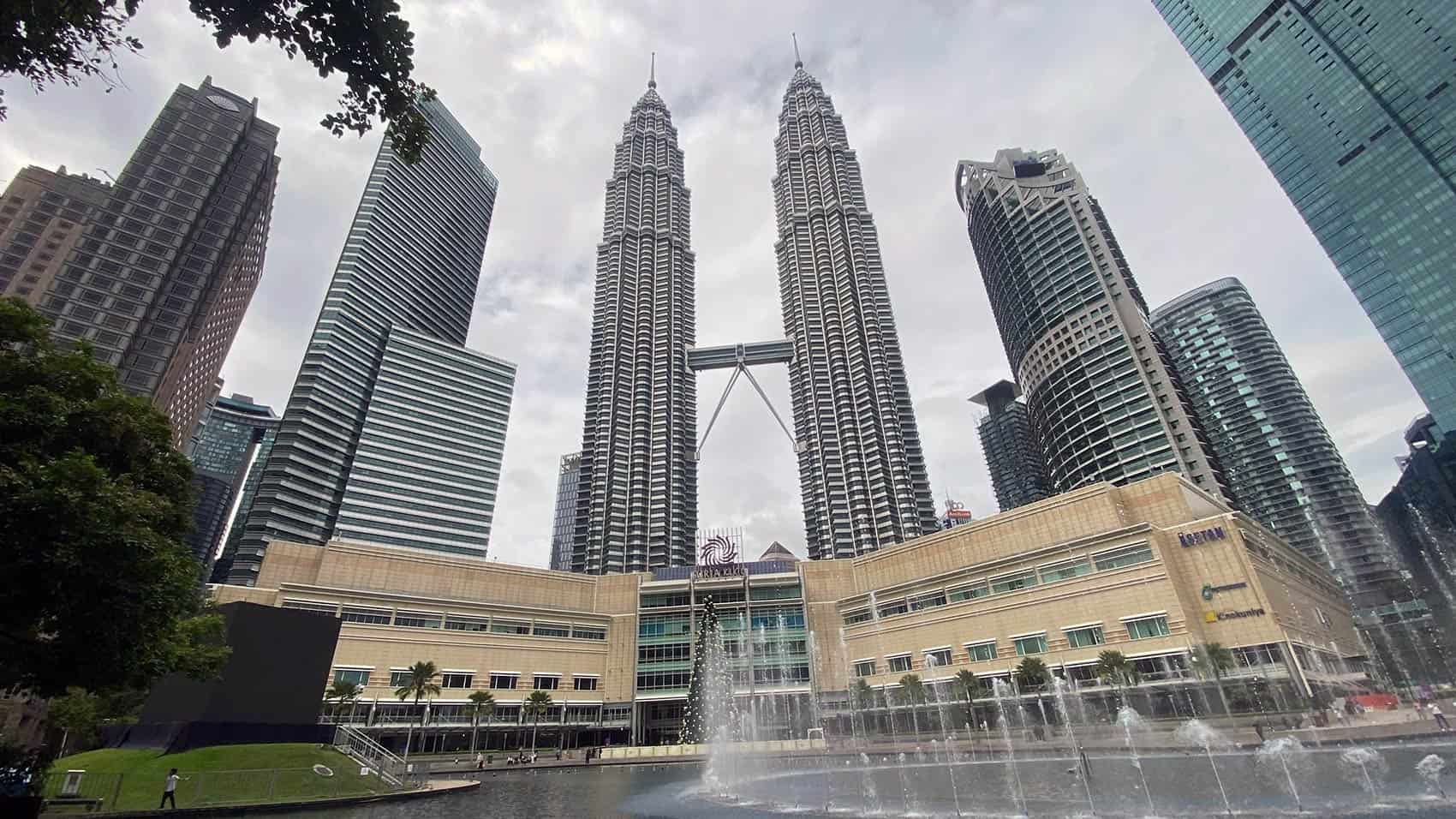 Petronas Twin Towers rising above Suria KLCC mall with the KLCC Park fountain in the foreground, a key stop on a Kuala Lumpur city tour