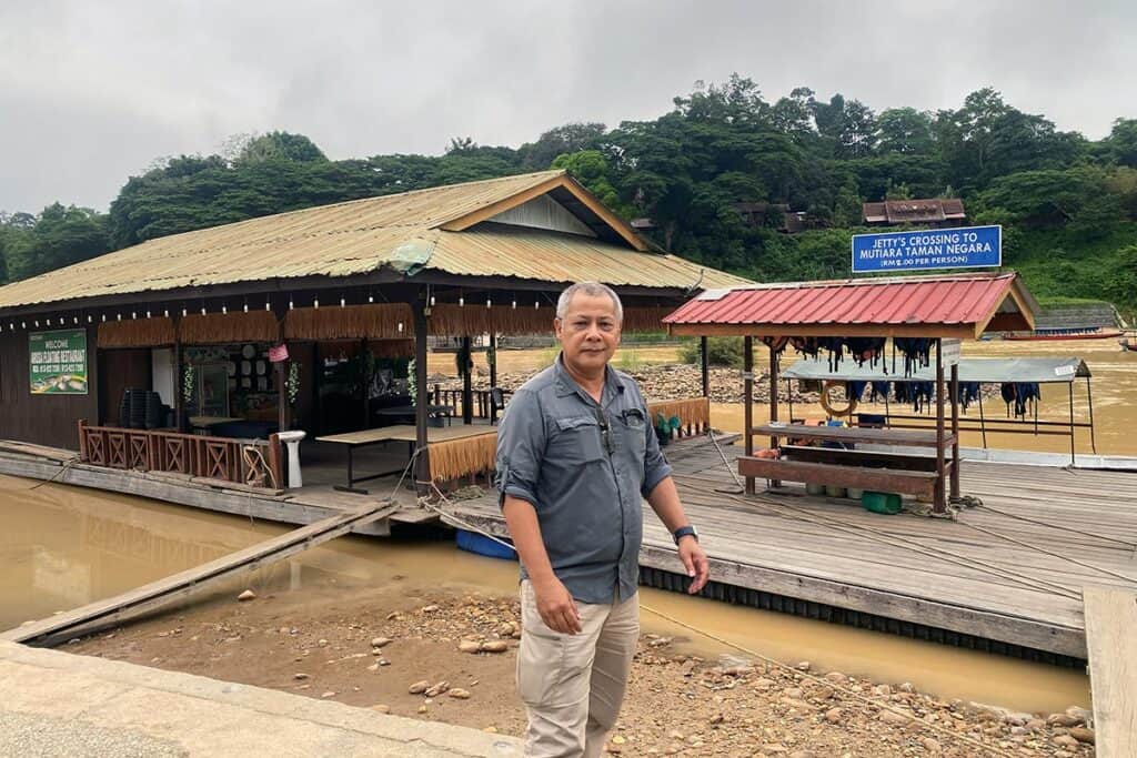 Anuar standing at the jetty crossing to Mutiara Taman Negara Resort in Kuala Tahan — Malaysia private tour and transfer specialist based in Kuala Lumpur