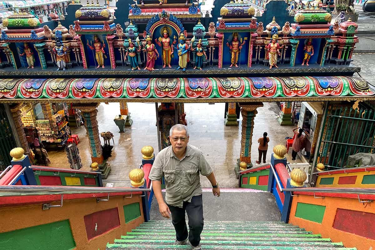 Anuar, local Kuala Lumpur tour guide, climbing the rainbow-coloured 272-step staircase at Batu Caves during a field visit