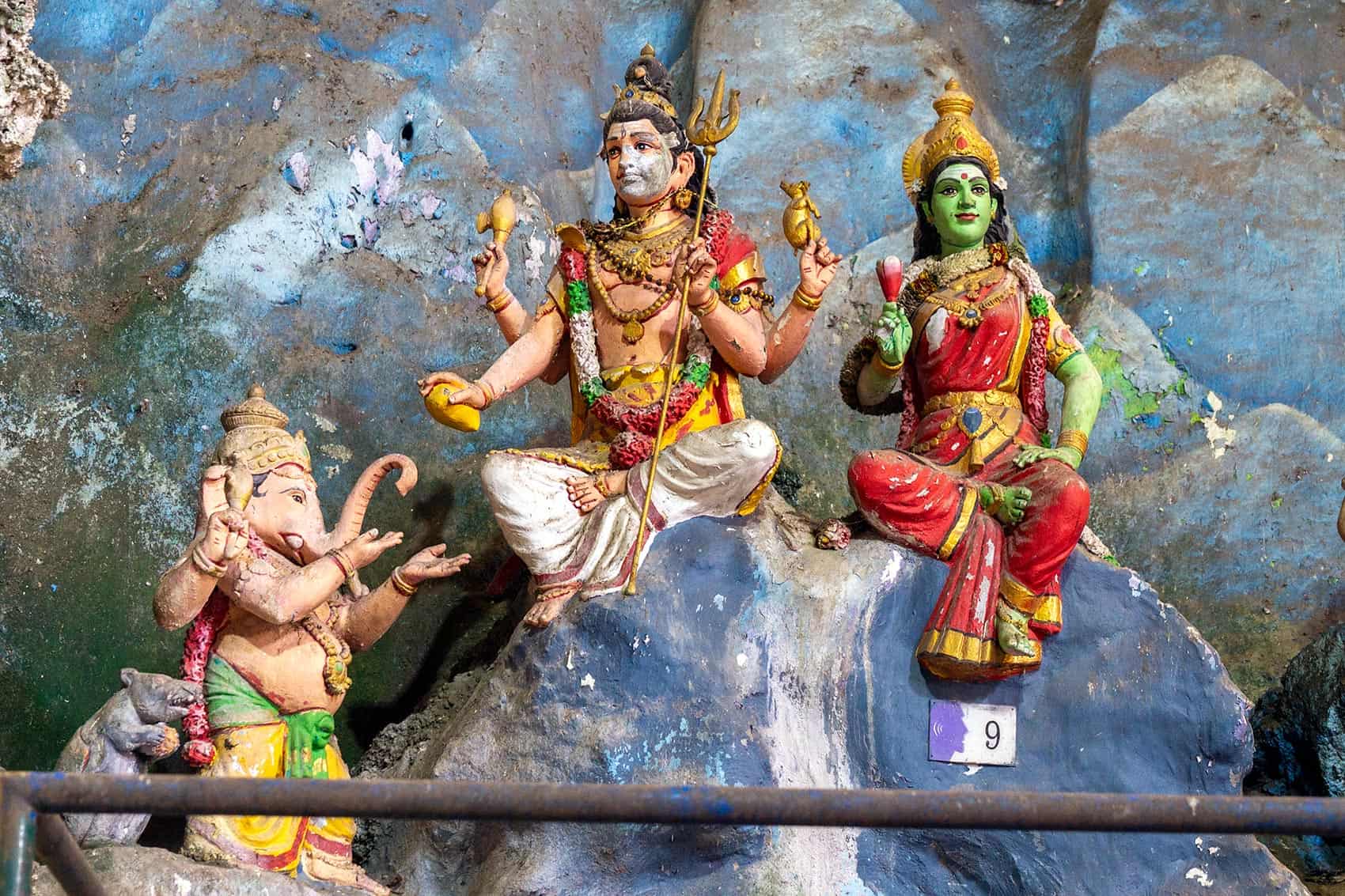 Painted shrine figures of Ganesh, Shiva, and Shakti at Batu Caves, part of a temple grouping rather than standalone statues